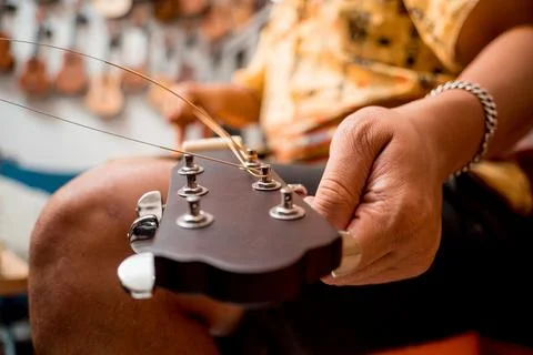 Young musician changing strings on a classical guitar in a guitar shop Stock Photos