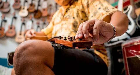 Young musician changing strings on a classical guitar in a guitar shop Stock Photos