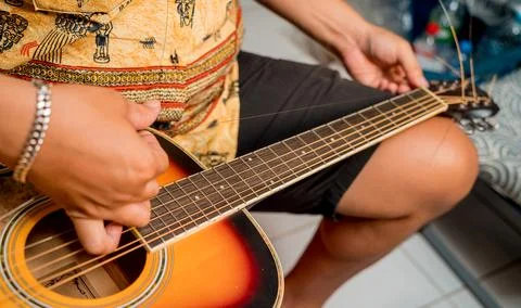 Young musician changing strings on a classical guitar in a guitar shop Stock Photos