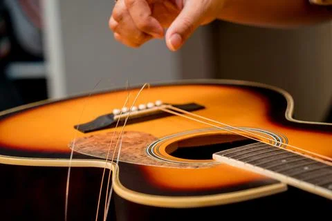 Young musician changing strings on a classical guitar in a guitar shop Stock Photos