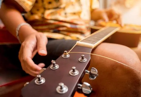 Young musician changing strings on a classical guitar in a guitar shop Stock Photos