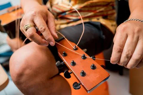 Young musician changing strings on a classical guitar in a guitar shop Stock Photos