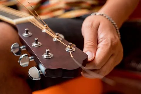 Young musician changing strings on a classical guitar in a guitar shop Stock Photos