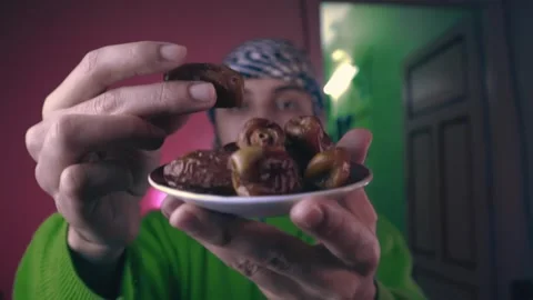 A young Muslim man eats dates for breakfast in Ramadan Stock Footage 299578158