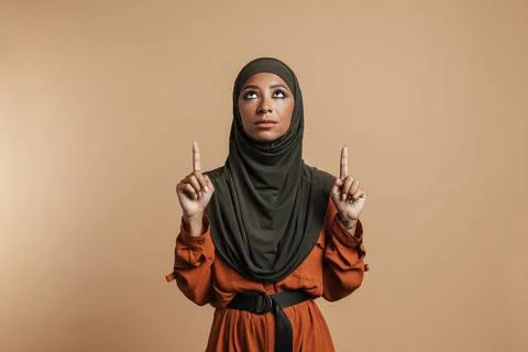 Young muslim woman in hijab looking and pointing fingers upward Stock Photos