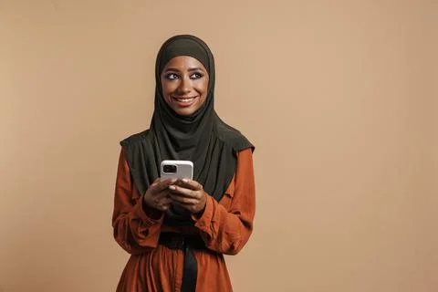 Young muslim woman in hijab smiling while using mobile phone Stock Photos