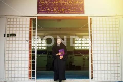Young muslim woman wearing black abaya dress holding The Holy Quran Stock Photos
