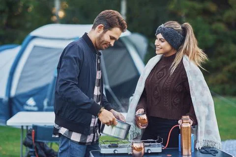 Young nice couple having fun on camping while cooking and eating Stock Photos