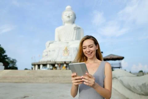 Young nice girl using tablet near white statue of Buddha in Phuket. Stock Photos
