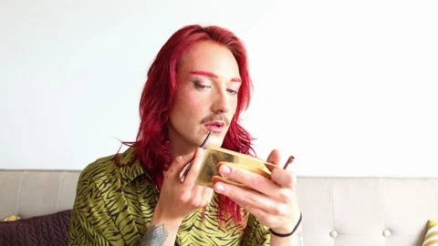 Young non-binary person applying lipstick on white background Stock Footage 309130299