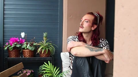 Young non-binary person relaxing on balcony with plants Stock Footage 309187487