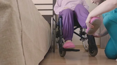 Young nurse caring of elder disabled woman in wheelchair Stock Footage 76223527