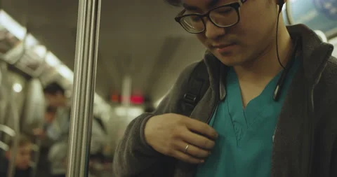 Young nurse inserts headphone on subway Stock Footage 130231850
