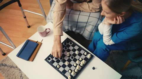 Young nurse playing chess with elderly man, memory-improving games for seniors Stock Footage 279177251