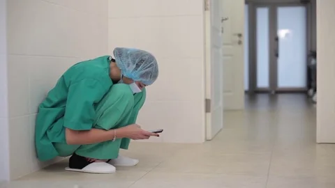 A young nurse is sitting in the operating room and using a smart phone Stock Footage 70807600