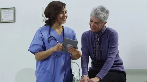 Young nurse speaking with patient using tablet Stock Footage 80131079