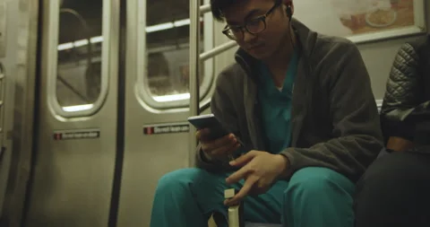 Young nurse using smart phone on subway Stock Footage 130233168