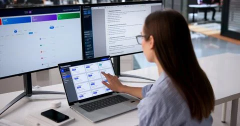 Young Office Manager Efficiently Organizing Multiple Documents On Computer Sc Stock Photos