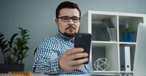 Young office manager in glasses with beard sits in modern office and responds to Stock Footage 147051859