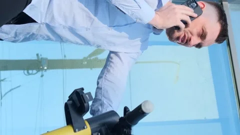 Young office manager talking on the phone using an electric scooter. Vertical Stock Footage 250028705
