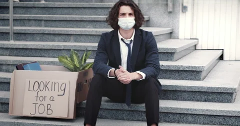 Young office worker dressed in formal clothes and medical mask sits on stairs in Видео 138697228