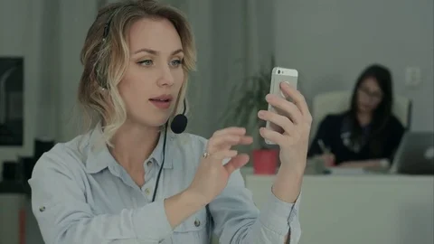 Young office worker in headset taking selfies on her phone Video stock 71125332