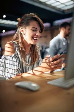 Young office worker looking at phone smiling, chatting, messaging. Stock Photos