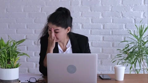 Young office worker looks intensely at laptop and takes off glasses to take Video stock 258347790