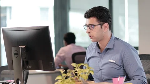 A young office worker or employee working on a computer in a modern office. Stock Footage 88065459