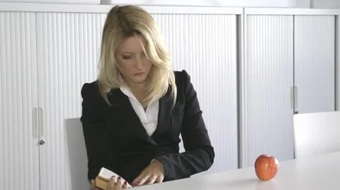 A young office worker reading a book and eating an apple Stock Footage 11059339