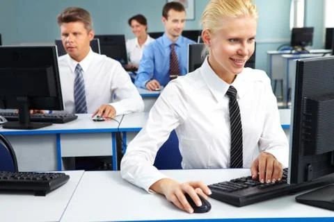 Young office worker sitting at computer and working among her colleagues Stock Photos