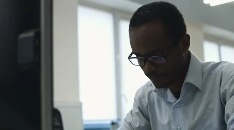 Young office worker wearing glasses using his laptop in the office Stock Footage 68305719