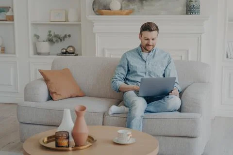 Young office worker working from home while sitting on couch with crossed leg Stock Photos