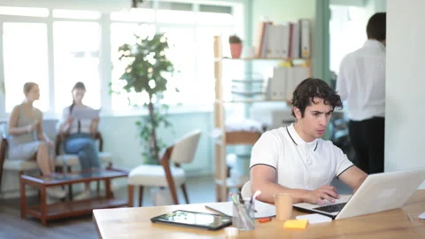 Young office worker works on laptop in a modern open-plan office Stock Footage 341432072