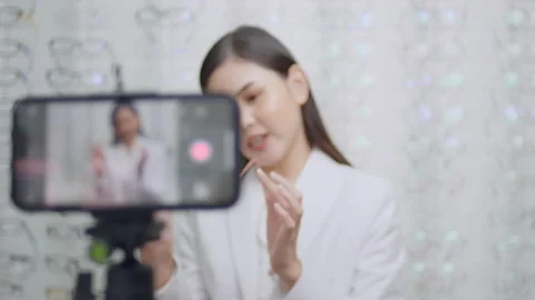 Young ophthalmologist doing live streaming via smart phone present new collec Stock Footage 188559863