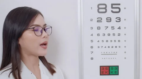 Young ophthalmologist doing visual test for customer using eye chart in optic Stock Footage 188558584