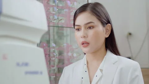 Young ophthalmologist doing a visual test for customer using autorefractor in Stock Footage 188560999