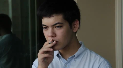 Young Oriental man smokes, throws away cigarette to camera disgusted Stock Footage 40499072