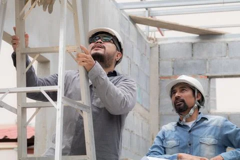 Young overweight engineering foreman climbing ladder inspect ceiling unfini.. Stock Photos