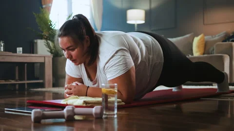 Young overweight woman doing exercise having an online class Stock Footage 218360953