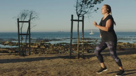 Young overweight woman running exercising caucasian female jogging on seaside at Stock Footage