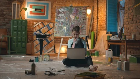 Young painter in apron browsing in the net while searching for painting hints Stock Footage 129315887