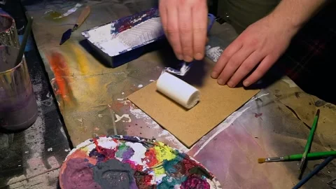 Young painter is preparing sheet on a stand, covering by layer of primer. Stock Footage 154349547