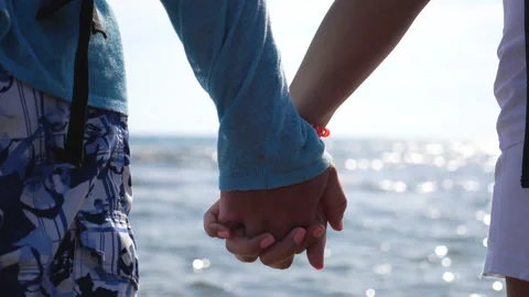 Young pair holding hands of each other standing on ocean coast. Couple of lovers Stock Footage 135256232