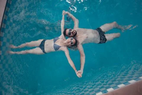 A young pair of lovers swims in the pool. Newlyweds relaxing in the water Stock Photos