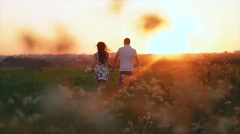 Young pair of runs in the sunset, the man picks up the girl and turns around Stock Footage 66557775