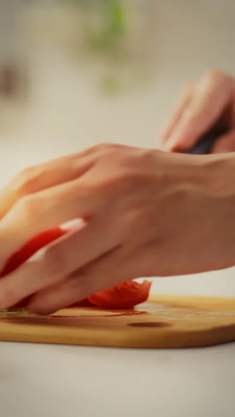 Young parent preparing healthy meal by cutting fresh tomatoes in a cozy kitc Stock Footage 331742720