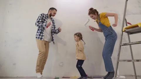 Young parents with daughter dancing with work tools during apartment Stock Footage 237804919