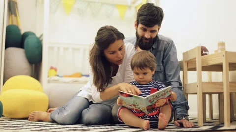 Young Parents Mom And Dad Reading Children Book To Baby Son On The Floor At Home Hi Res 64522971