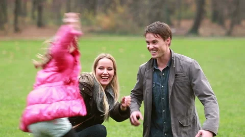 Young parents playing with daughter in park Stock Footage 59554553
